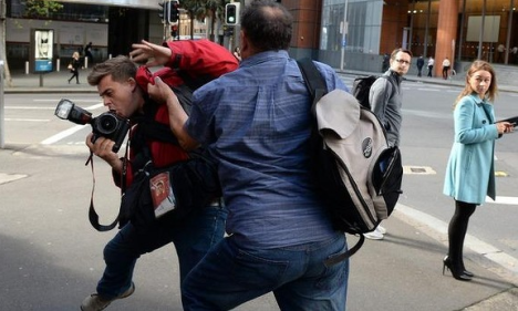 Photographer Sam Mooy tries to fend off the attack. Photo: AAP