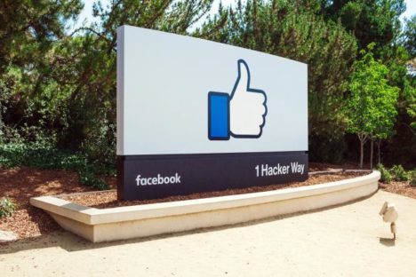 Facebook like hand front of company sign