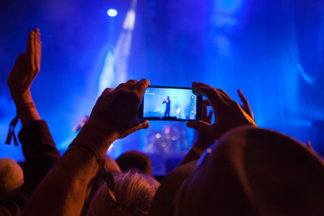 Person capturing a video on a mobile phone at a music festival.