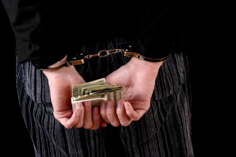 Man with handcuffs and dollars on black