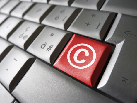 Digital copyright web content and Internet concept with copyright symbol and icon on a red laptop computer key for blog, website and online business.