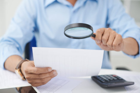 Financial adviser looking at figures with magnifying glass