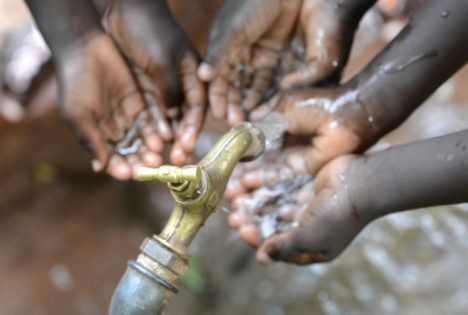 Hands of African black boys and girls with water pouring from a tap. Water scarcity or lack of safe drinking water is one of the world's leading problems affecting more than 1 billion people globally, meaning that one in every six people lacks access to safe drinking water. This affects people and especially children in Africa.