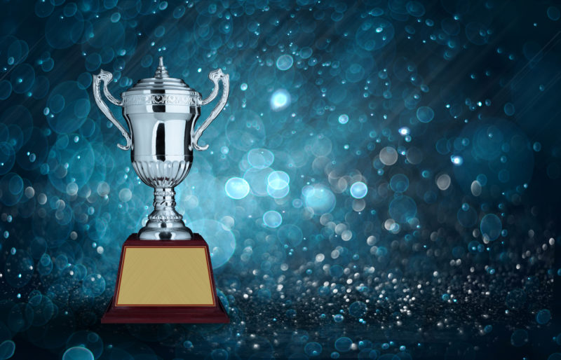 abstract silver trophies with blue bokeh lighting. copy space ready for your trophy design.