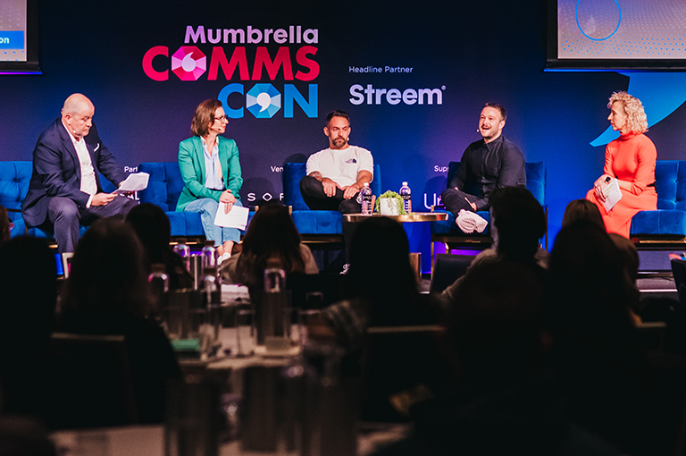 Buy a ticket for CommsCon. Panelists in discussion to a full room.
